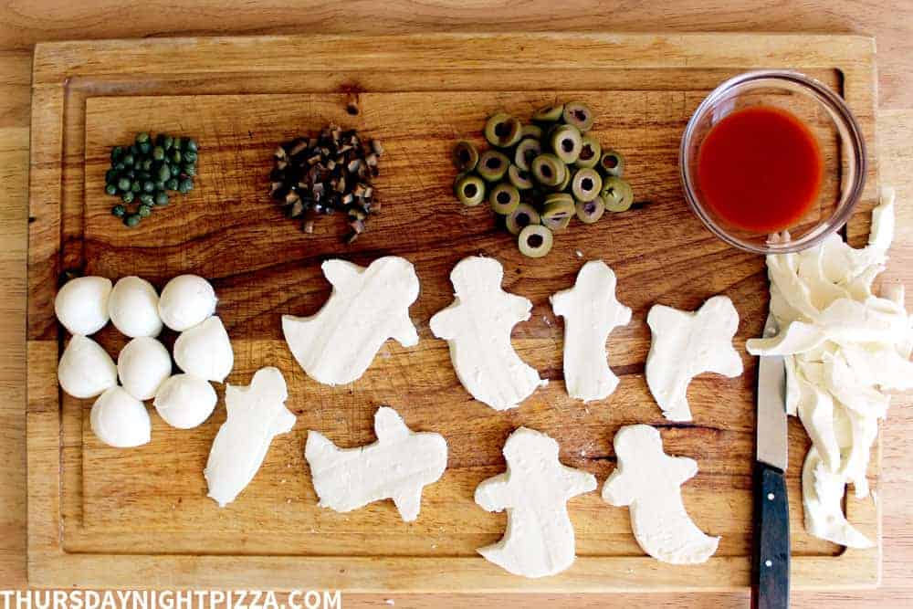 Cutting mozzarella for ghost Halloween pizza