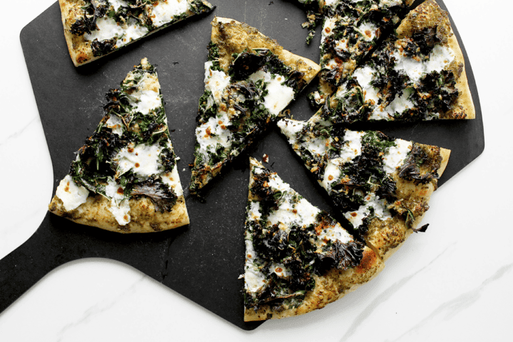 crispy kale and pesto pizza slices on pizza peel