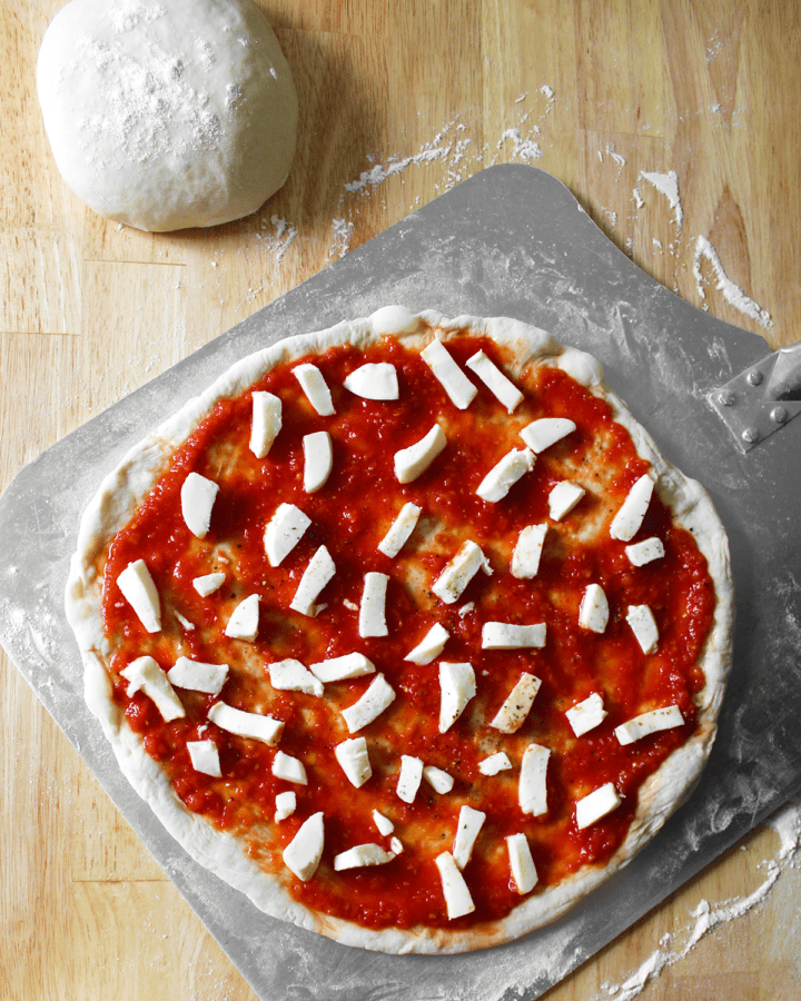 Neapolitan pizza dough, stretched out and topped