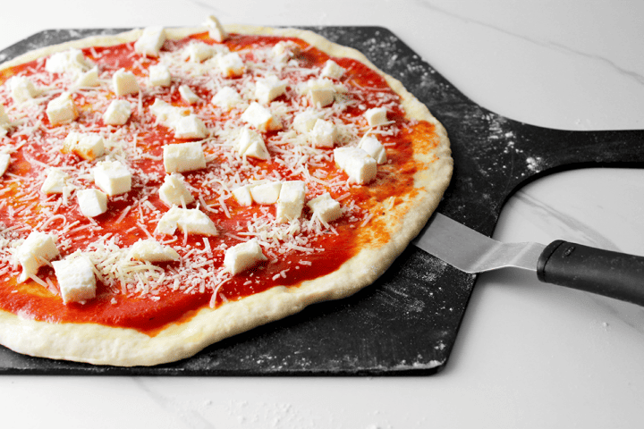 using an offset spatula to loosen dough from a floured pizza peel